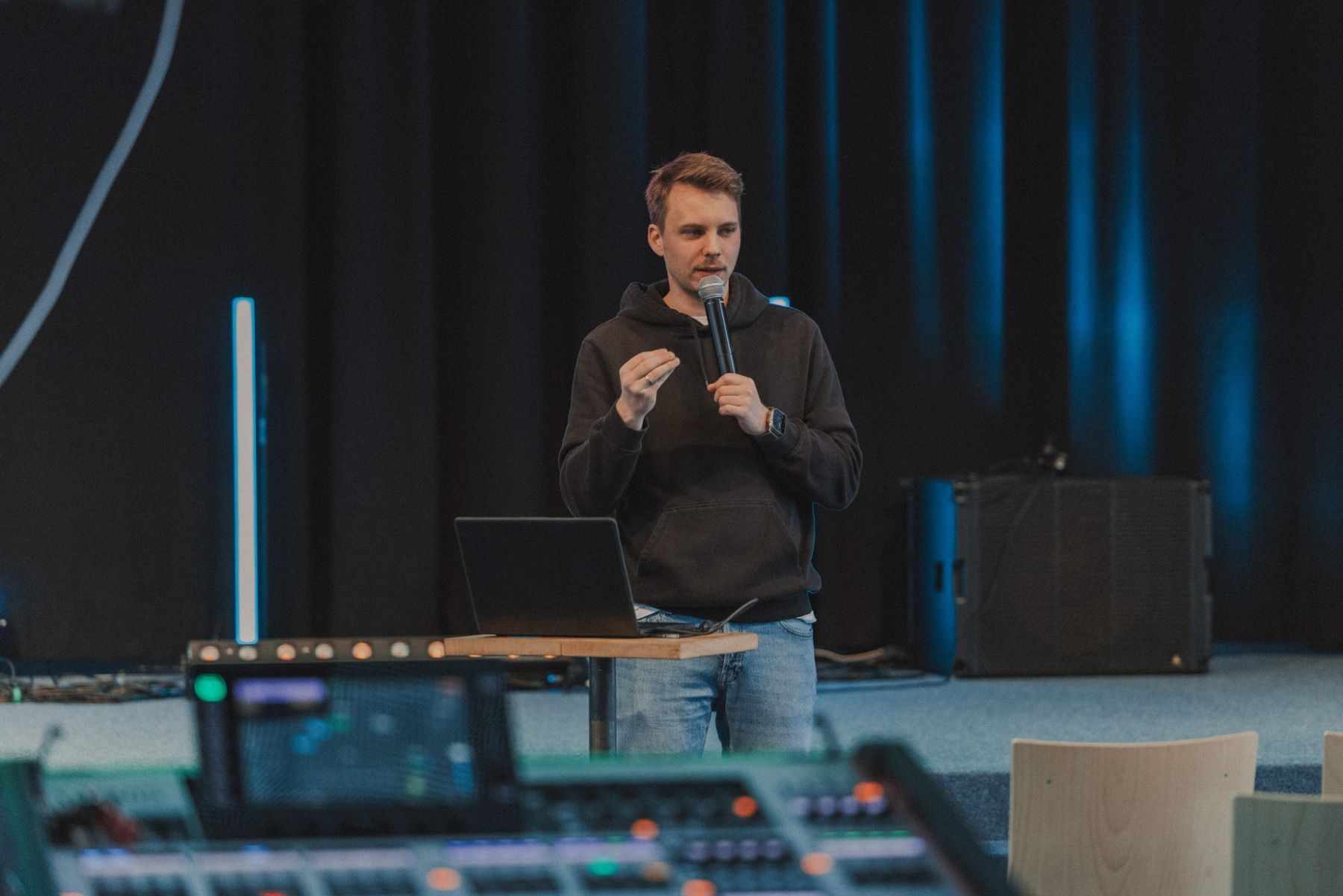 Lauritz Leiber hält mit Mikrofon einen Workshop für ein Technikteam, im Vordergrund ein Mischpult